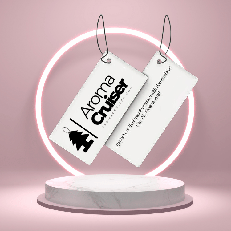 Two rectangular Aroma Cruiser air fresheners with branding and promotional message, suspended in front of a neon-lit circular display, highlighting personalized car air fresheners for business promotions